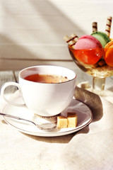 Cup of tea with macaroons on table, close up
