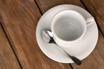 Empty cup with tea spoon on wooden background