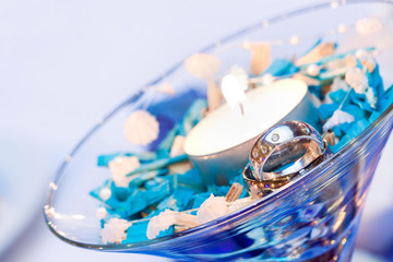 wedding rings in a glass cup with a candle