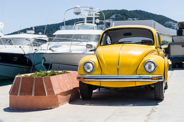Retro yellow car with luxury yachts on background