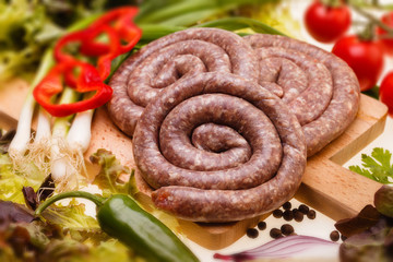 Bulgarian, raw sausages with vegetables on wooden board