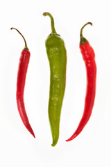 one green and two red peppers on a white background