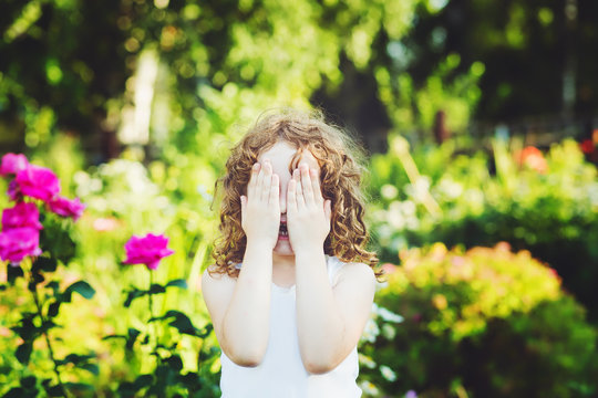 Little girl closed face with her hands, weeping, or playing hide