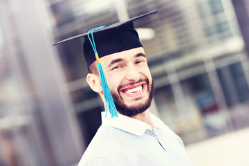 Cheerful graduate outside modern building