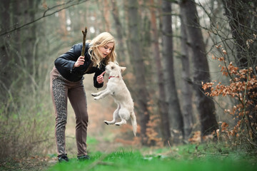 Fototapeta premium Blond girl playing with her puppy in the forest