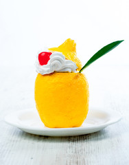 Fototapeta na wymiar Lemon with lemon cream, candied cherry and mint on a plate