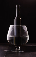 Wine bottle in the big wine glass isolated