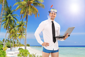 Businessman with a diving mask holding a laptop and standing on