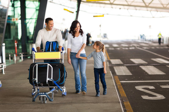 young family at airport with a trolley full of luggage