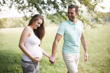 Obraz premium Pregnant woman with husband walking on meadow