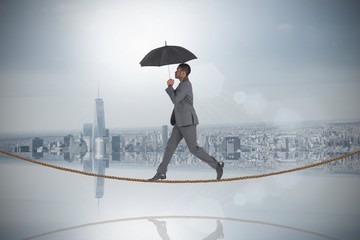 Composite image of businessman walking tightrope