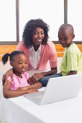 Cute siblings using laptop together with mother