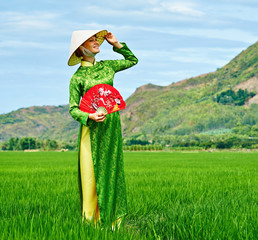 Woman walking in a rice field in traditional long dress