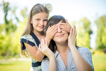Smiling girl covering her mother eyes