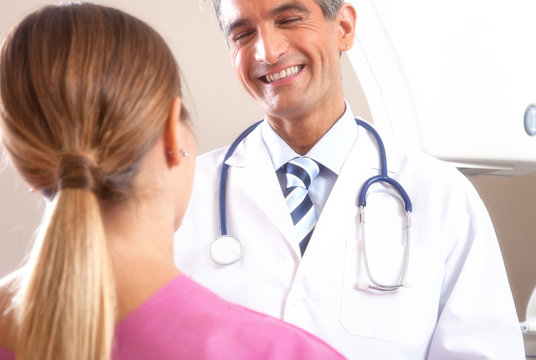 Happy young male doctor speaking with female patient undergoing