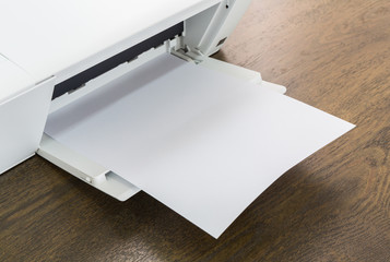 Printer with blank paper on a wood table