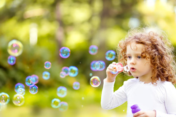 A little girl blowing soap bubbles