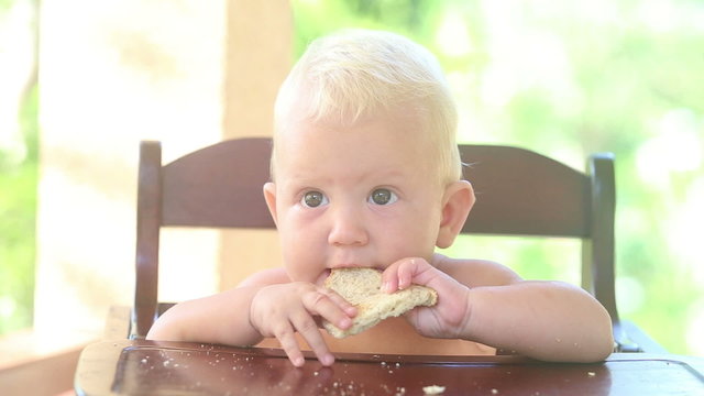 baby eat bread on chear