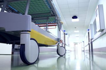 Bed on wheels waiting in the illuminated hospital corridor