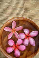Fototapeta na wymiar frangipani in water wooden bowl on Brown straw mat