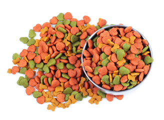 Silver bowl full and overflowing with dog food bits on a white b