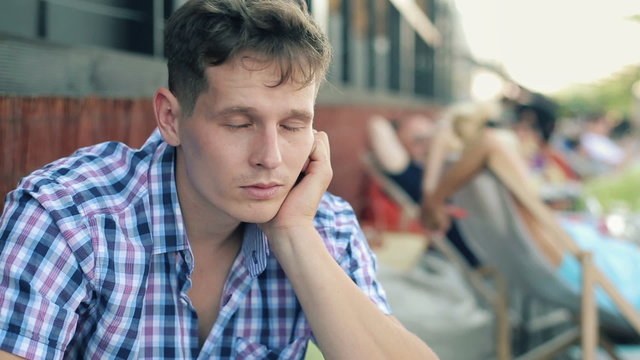 Sad, pensive man sitting in crowded outdoor cafe