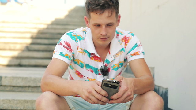 Young man texting, using smartphone in the city