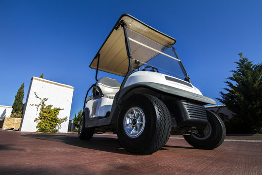 Close up view of a white golf cart parked on the road.