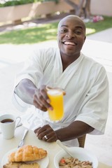Fototapeta na wymiar Handsome man in bathrobe having breakfast outside