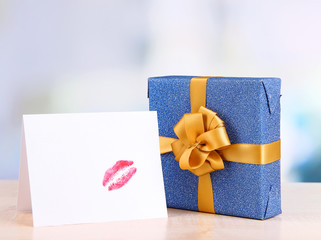 Gift with card for loved one on table on room background