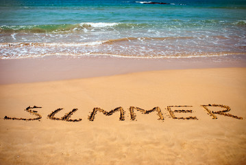 summer handwritten inscription in sand on a beach ocean