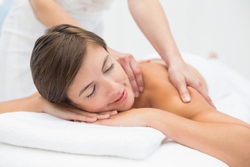 Fototapeta na wymiar Attractive young woman receiving shoulder massage at spa center