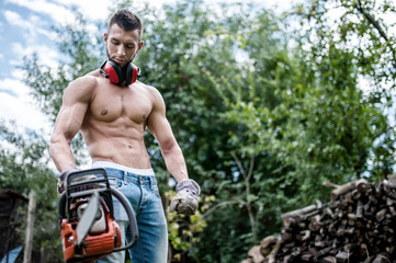 portrait of sexy man with chainsaw and protective gear ready