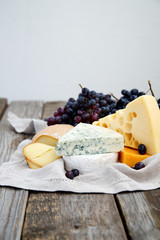Set of cheeses with a bottle of red wine and dark grapes