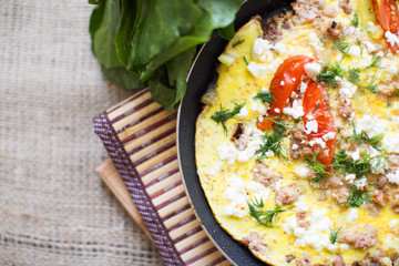 Omelet with vegetables and minced meat fried in a pan