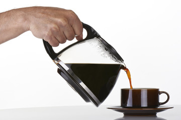 man's hand holding and pouring coffee into a brown cup - Powered by Adobe