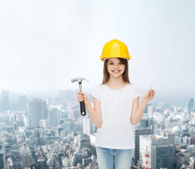 smiling little girl in hardhat with hammer