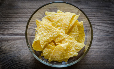 Heap of corn chips in the glass bowl on the wooden background