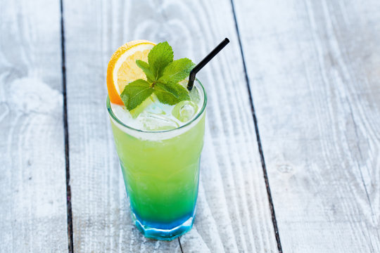 blue green cocktail with orange and mint