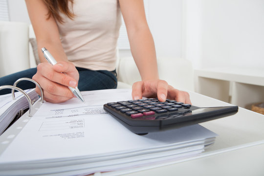 Woman Calculating Home Finances At Table