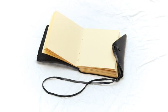 An Open Leather Bound Black Journal Outdoors On Table, Revealing