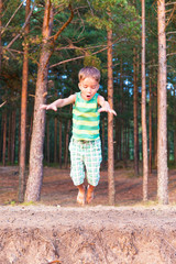 European boy jumping down the cliff forest