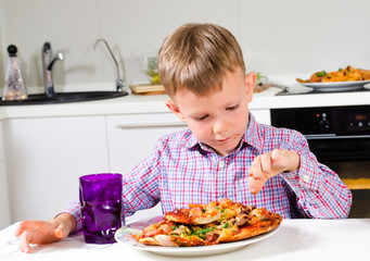 Little boy eating a big plate of pizza