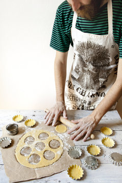 bearded young man with apron making shortcrust pastry