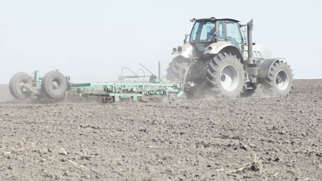 gray tractor go on black earth field 