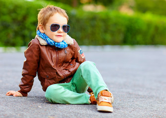 stylish boy in leather jacket posing on the ground