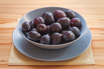 Ripe Plums on Wood Background.