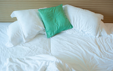 pillows and white sheets on messy bed
