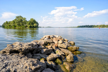 Fototapeta na wymiar A view of the Dnieper River in Kiev during summer. Stones in the foreground and transparent clear water