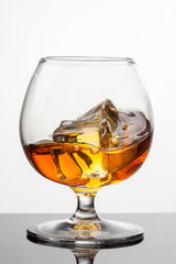 Splash of whiskey with ice in glass isolated on white background